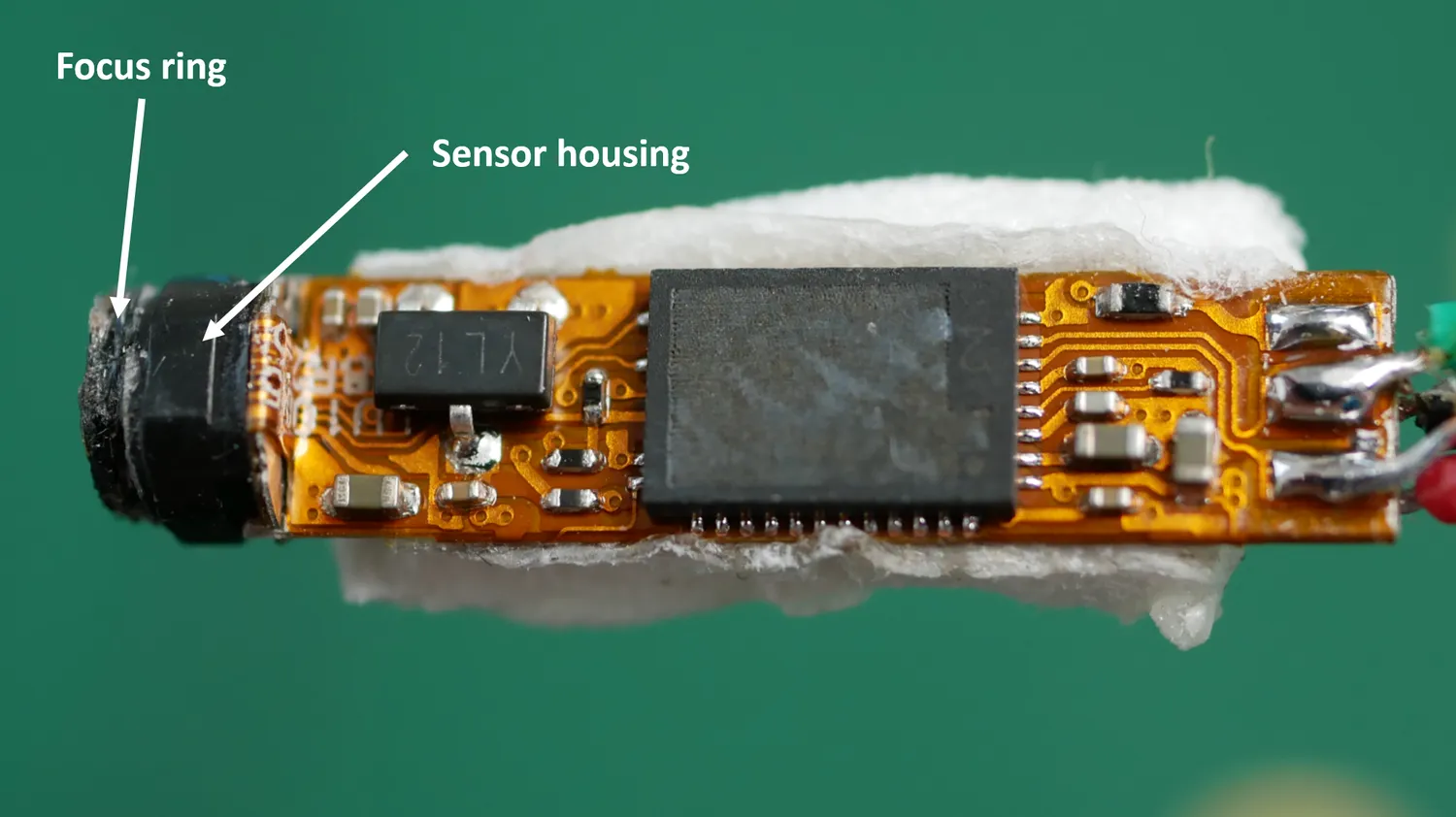 The endoscope module out of its tube, with the focus ring and sensor housing labelled at the lens end of the flex PCB