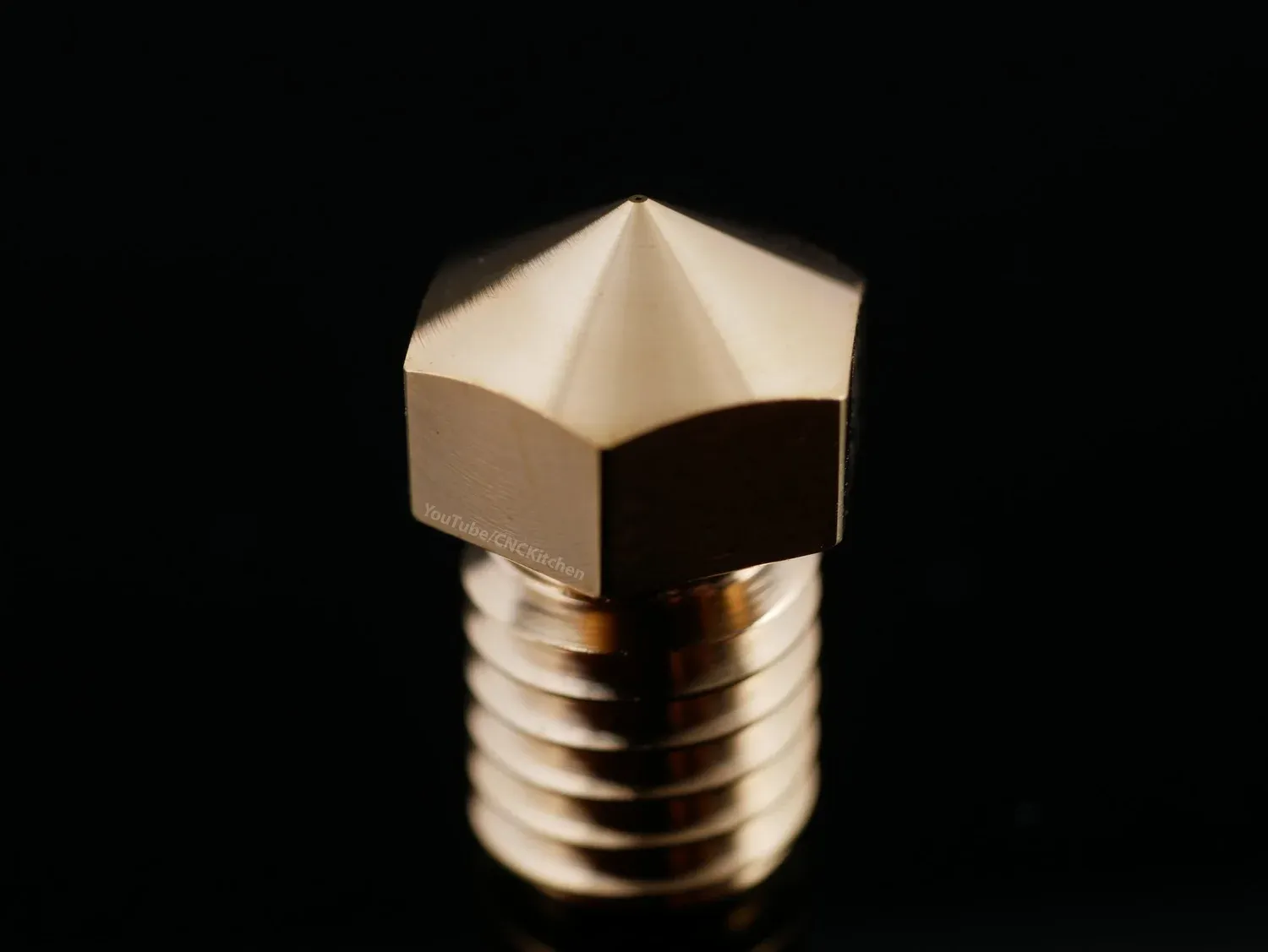 Macro of the Kaika nozzle tip, the 0.1 mm orifice a pinprick at the centre of a mirror-finished cone