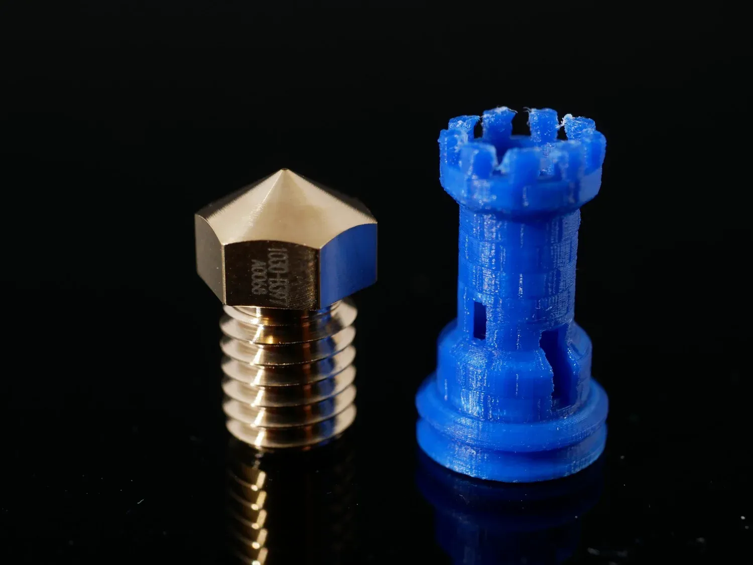 A tiny rook printed at 0.1 mm, its battlements resolved but fuzzy at the top