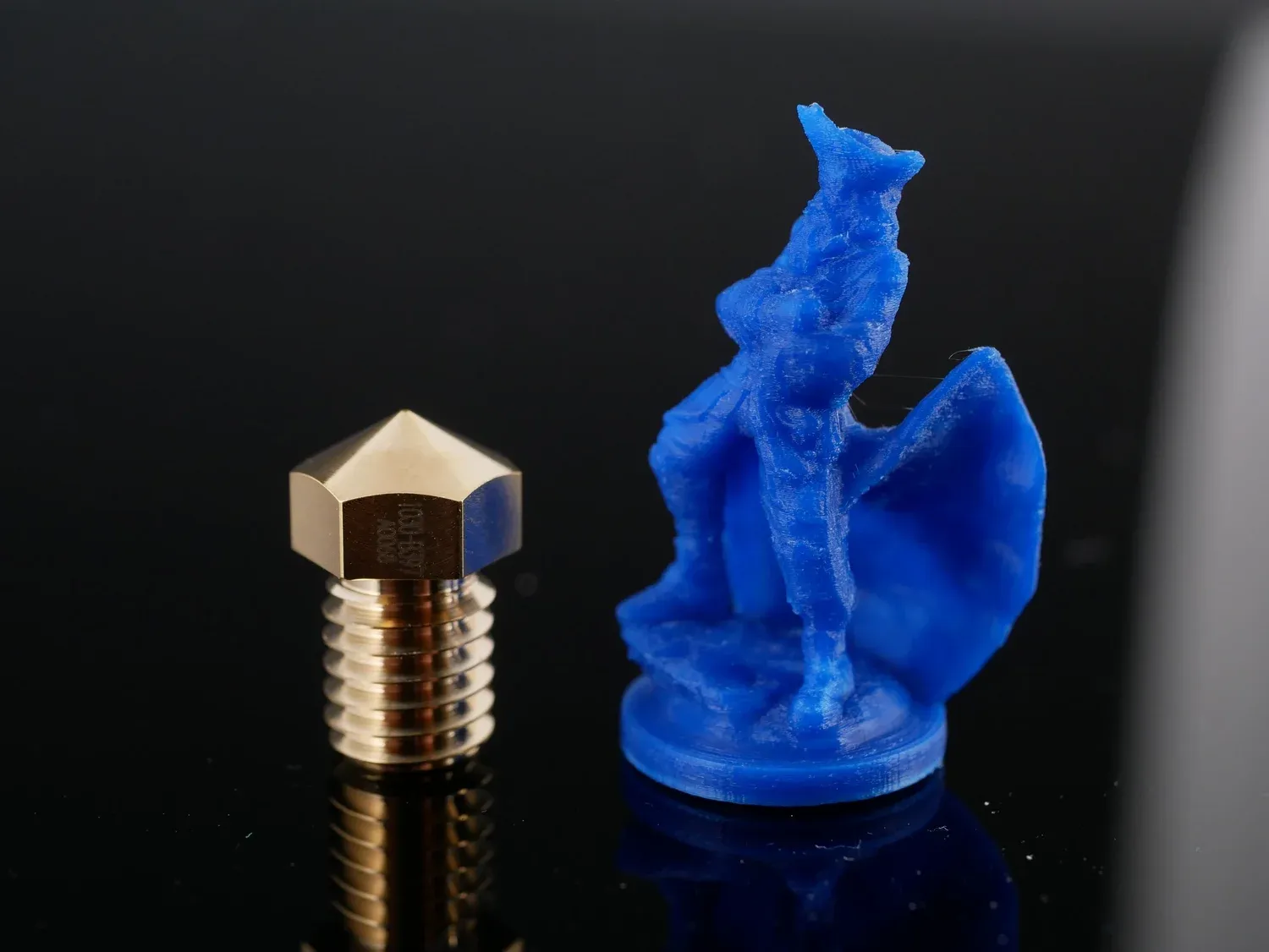 A miniature figure with a cape, printed at 0.1 mm next to the nozzle for scale