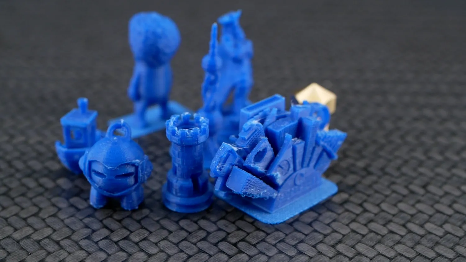The whole set of blue FDM miniatures together on a dark mat