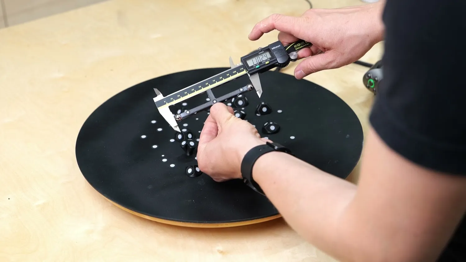Digital calipers measuring a DIY ball bar on a scanning table