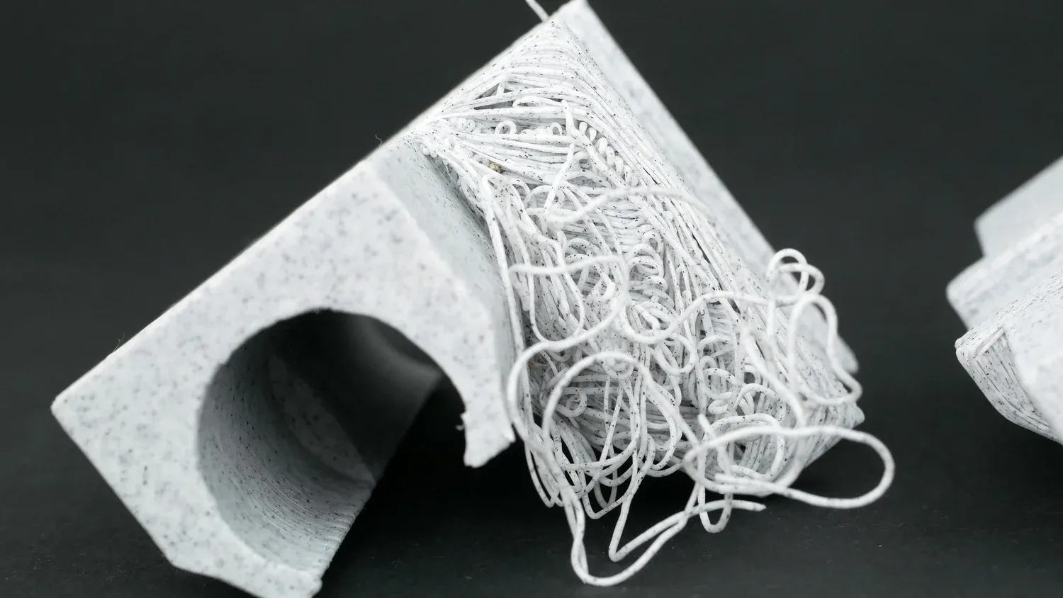 The same part printed with nothing underneath, the overhang collapsing into a tangle of loose strands