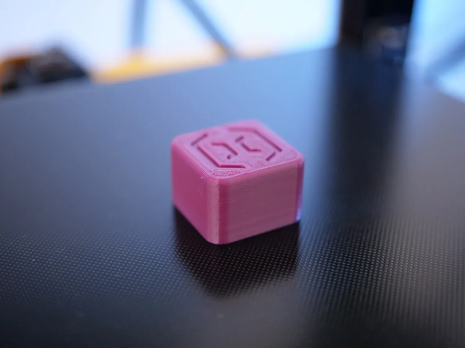 A calibration cube with the CNC Kitchen logo embossed on top