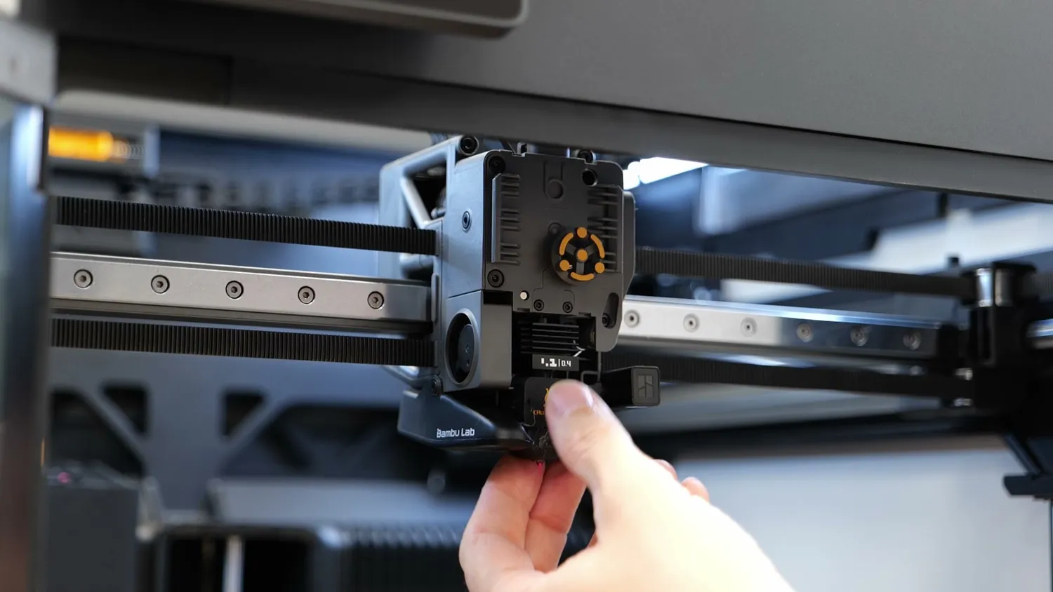 A hand releasing the hotend clip on the H2S toolhead