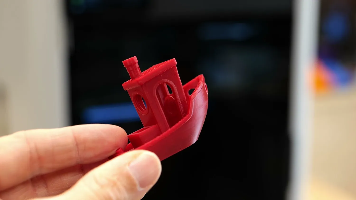 A red 3DBenchy held in a hand