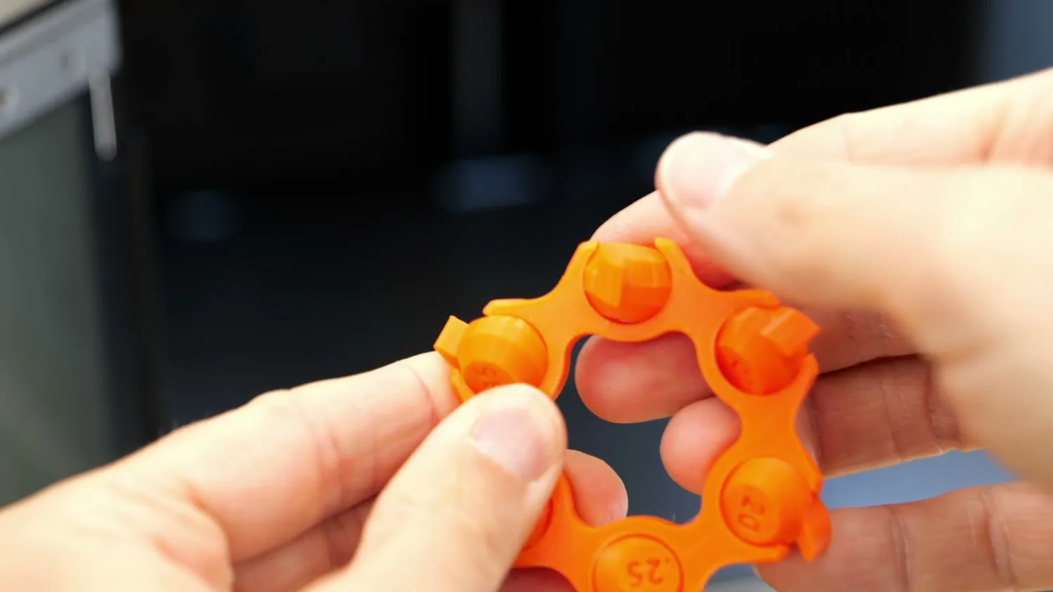 An orange tolerance test ring being turned in two hands