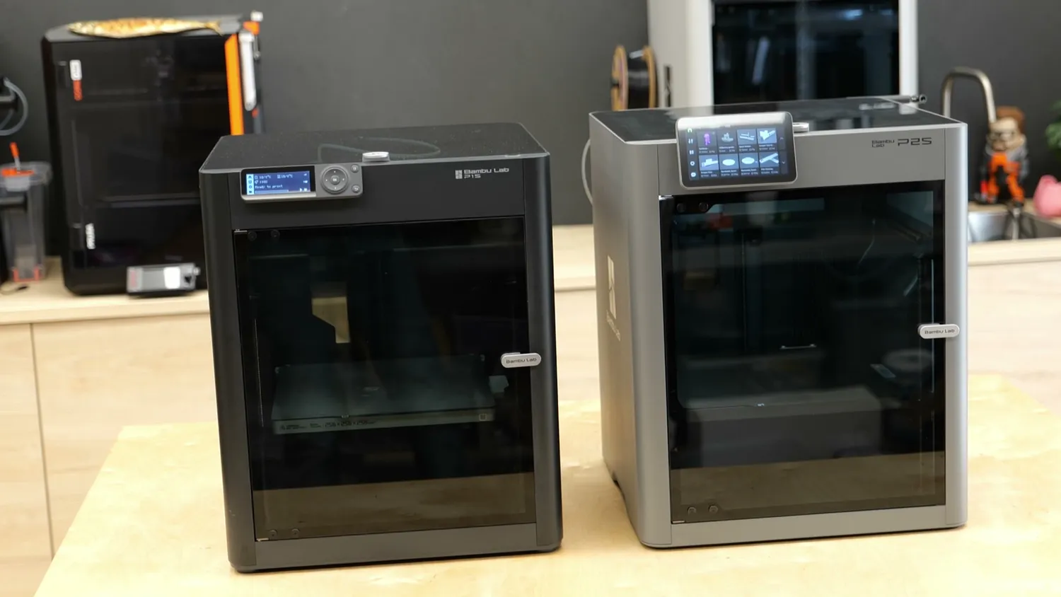 The dark P1S next to the silver P2S on a workbench