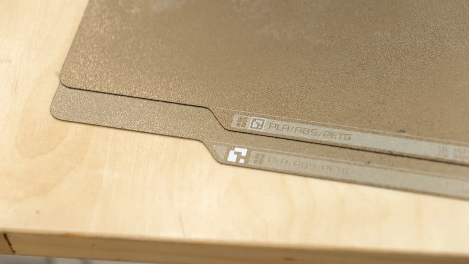 Two build plates overlapping, both showing a printed data matrix and PLA/ABS/PETG marking