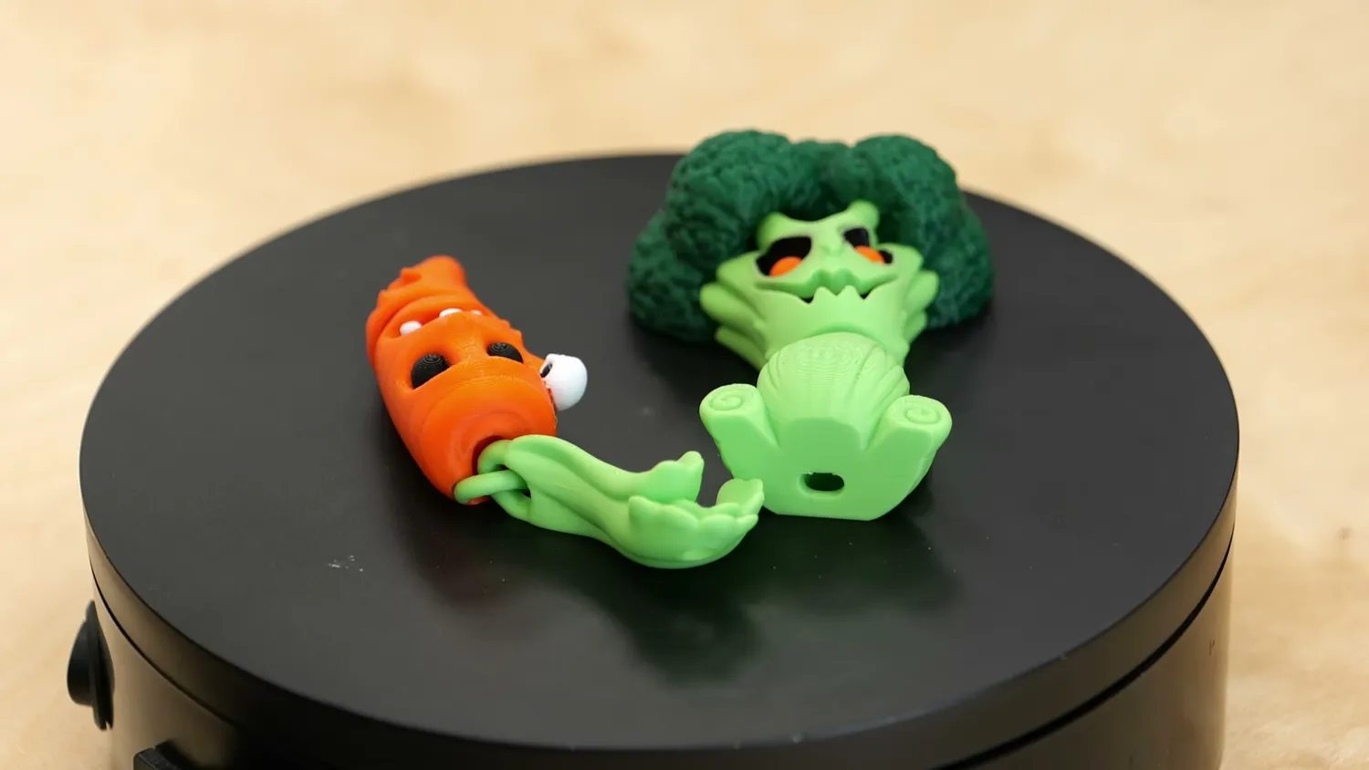 A print-in-place flexi carrot and a flexi broccoli on a black turntable