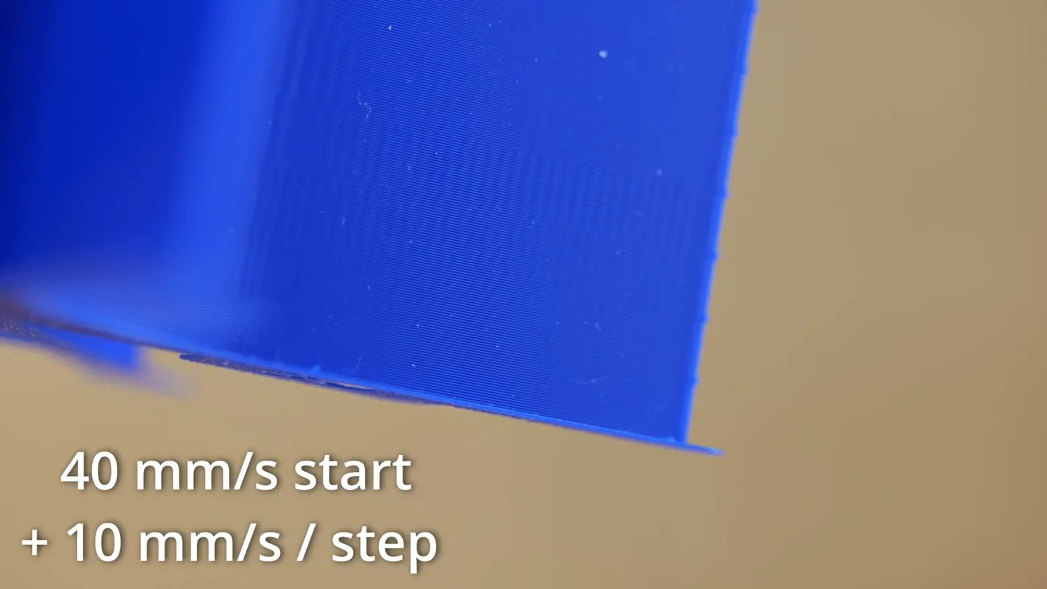 Close-up of a flat blue printed wall showing fine vertical banding, overlaid with the text 40 mm/s start plus 10 mm/s per step