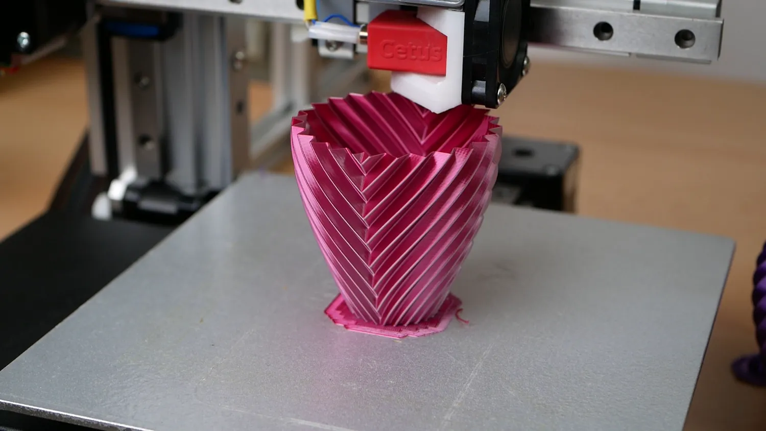 A pink chevron-ribbed vase on the Cetus bed