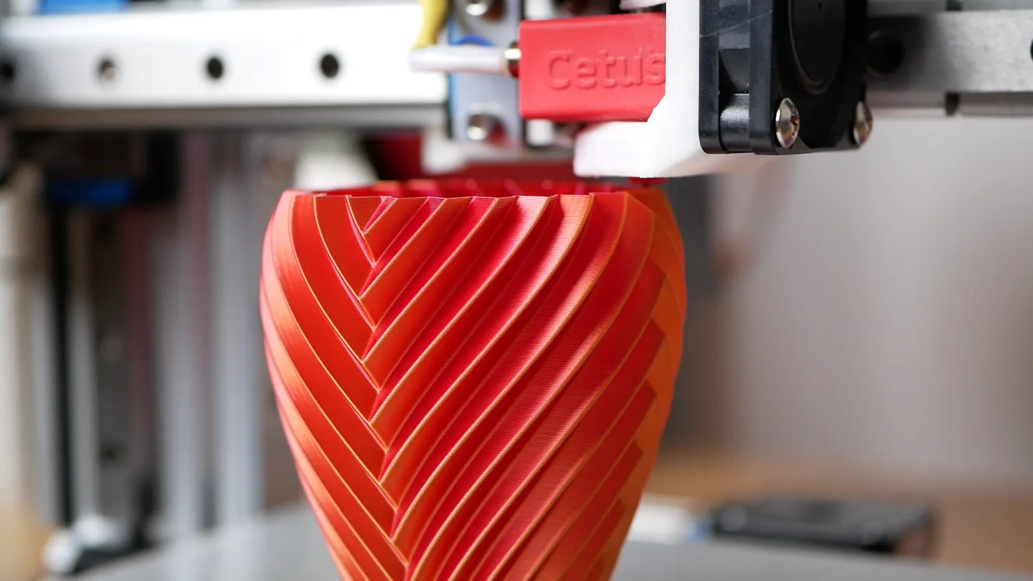 Close-up of a red and gold vase on the machine, the ribs crisp with no salmon skin