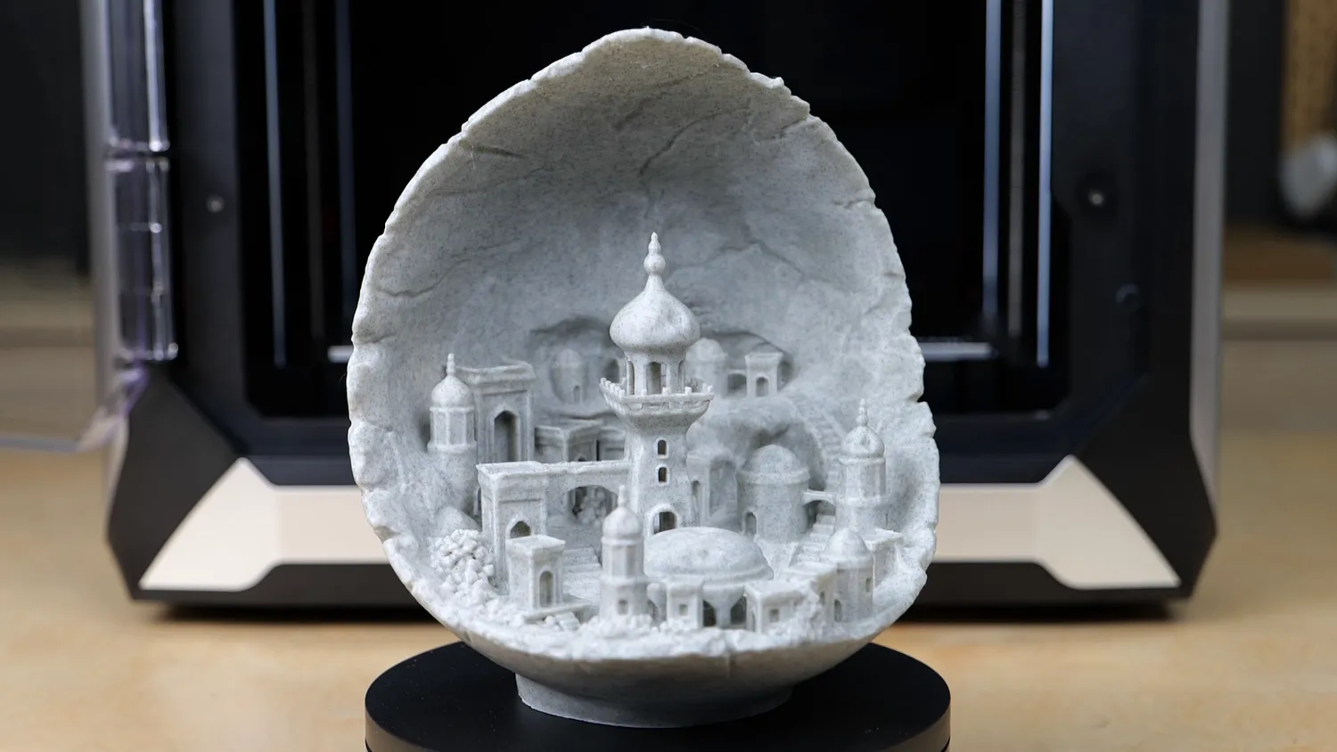 Stone-look print of a domed city inside a cracked shell, in front of the QIDI X-Max 3