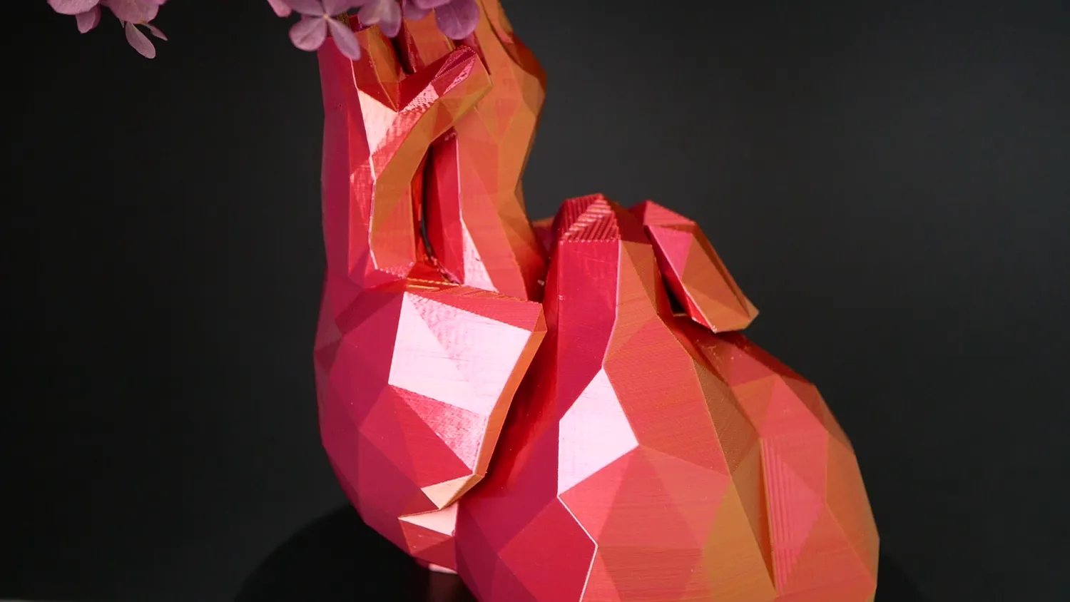 Low-poly rabbit in red and orange, each facet reading a different shade depending on which way it faces