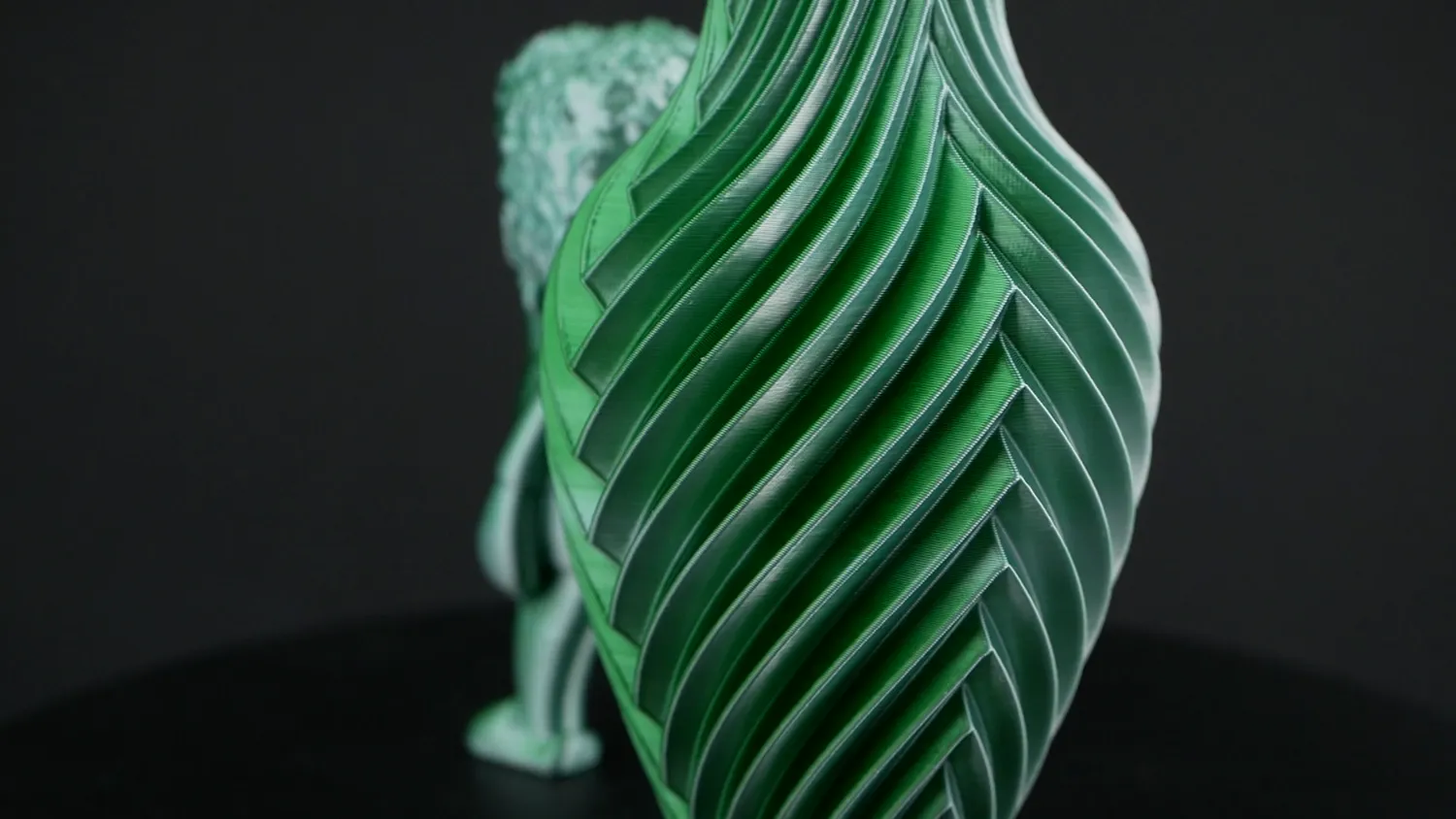 A green and white vase with the Marvin behind it out of focus