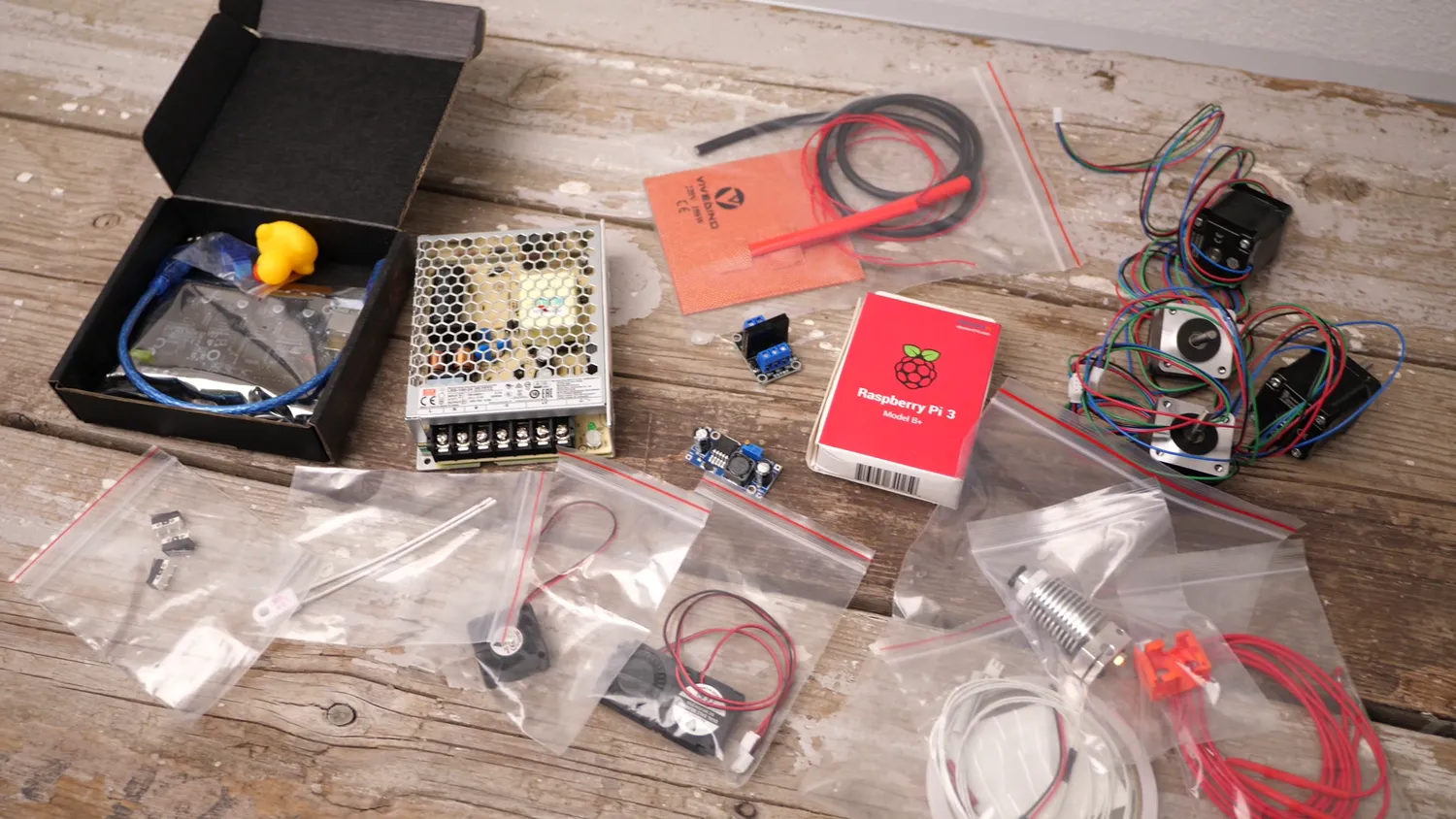 The full kit laid out: power supply, Pi, bed heater, hotend, fans and bagged hardware