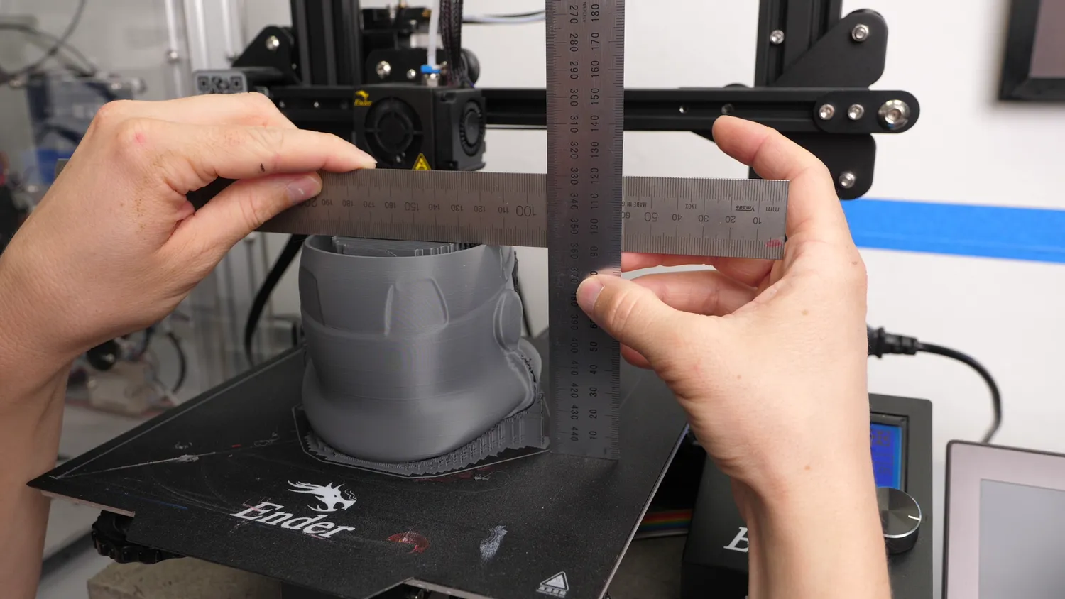 Two steel rulers used as a makeshift square to read the height of a grey print off the bed