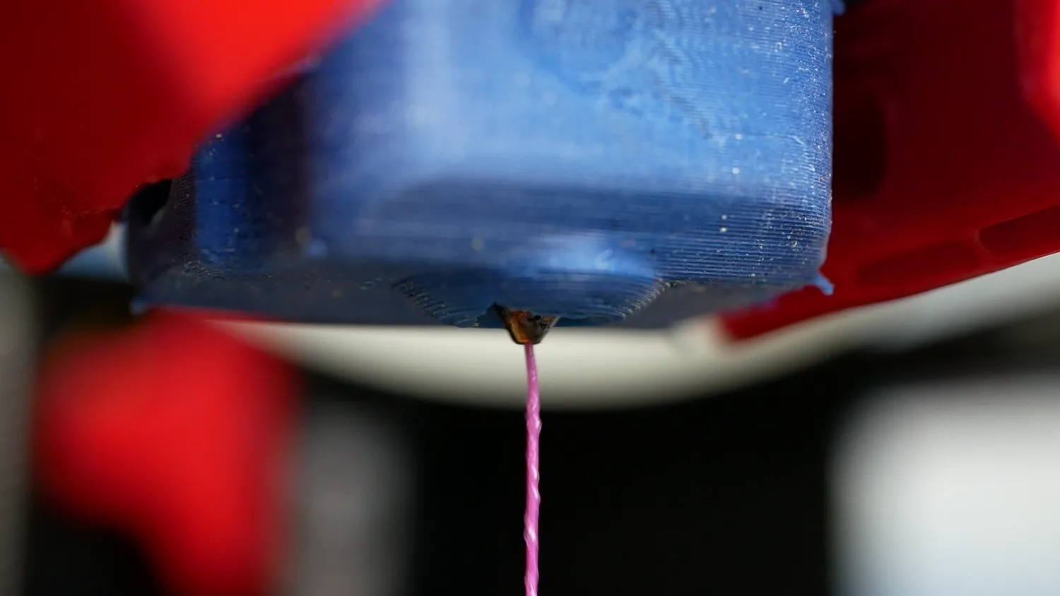 The homemade silicone sock on the heater block while extruding pink filament