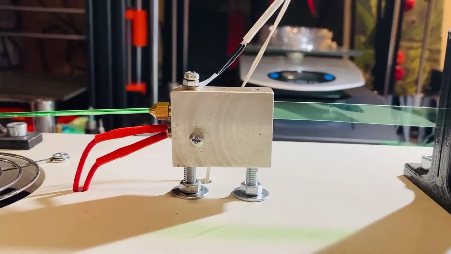 Pultrusion in action: a green bottle strip pulled through a nozzle in a heated aluminium block