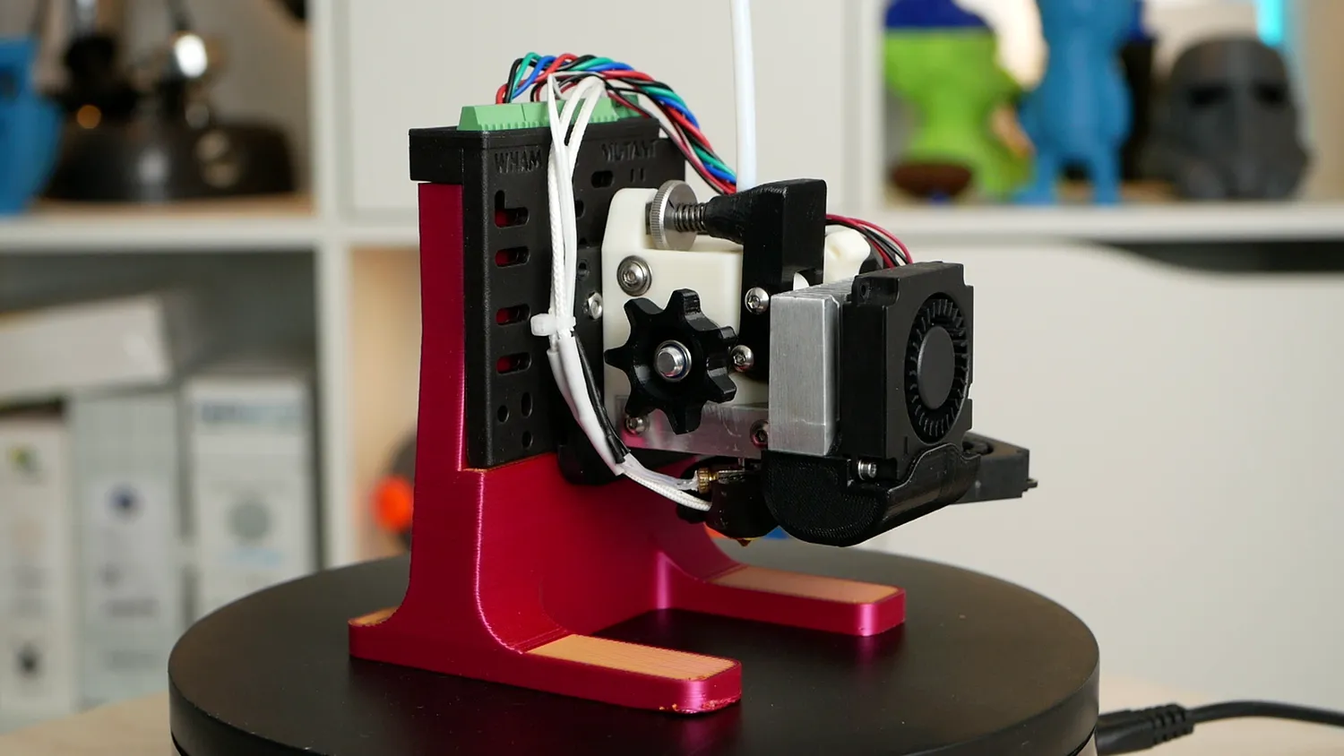 The OmniaDrop extruder on the bench, its tension thumbscrew on top