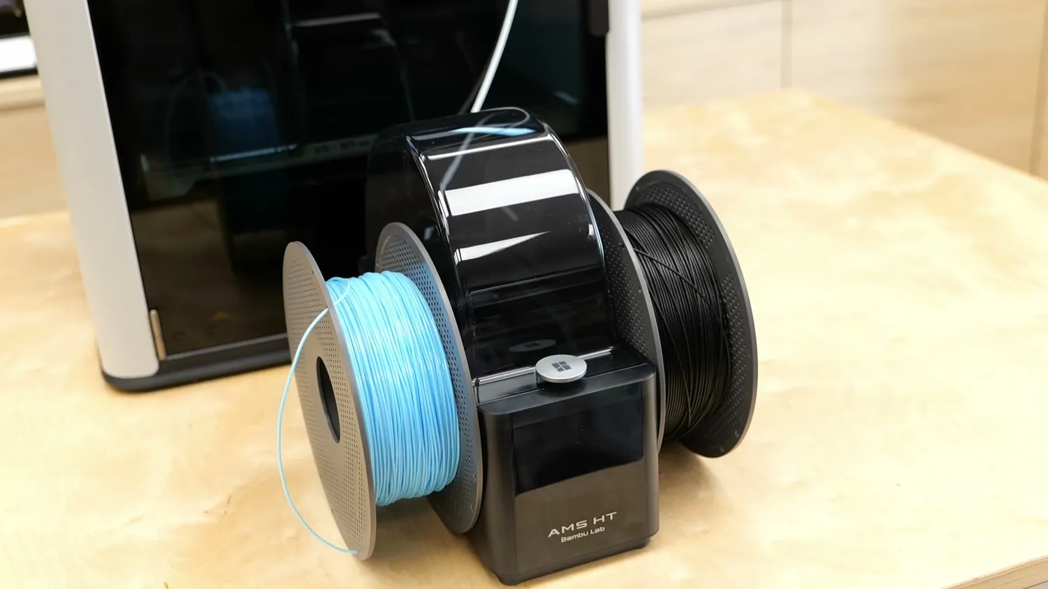 The single spool Bambu Lab AMS HT standing in front of the H2D