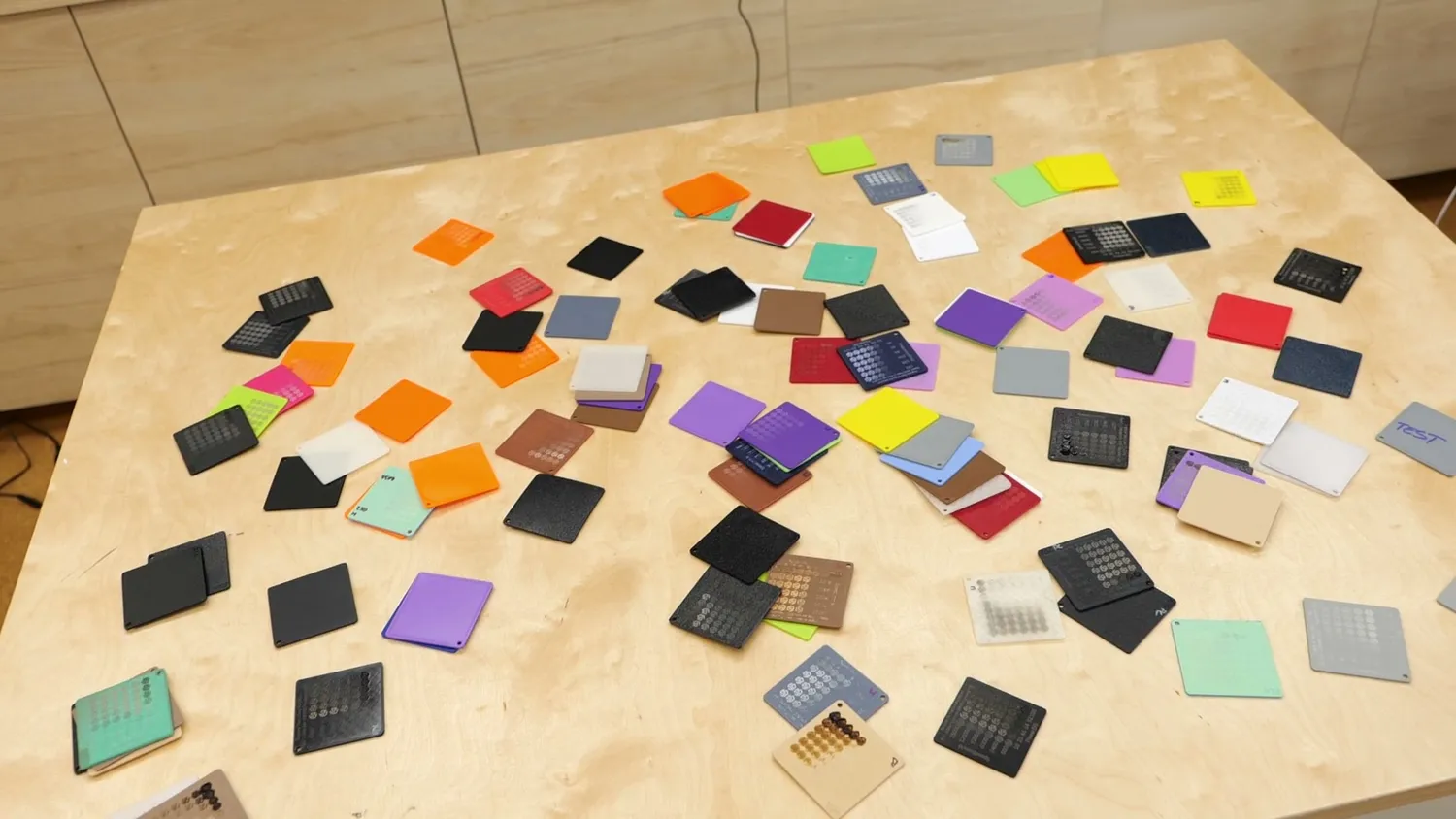 Dozens of colorful 3D printed test plates spread out on a workbench