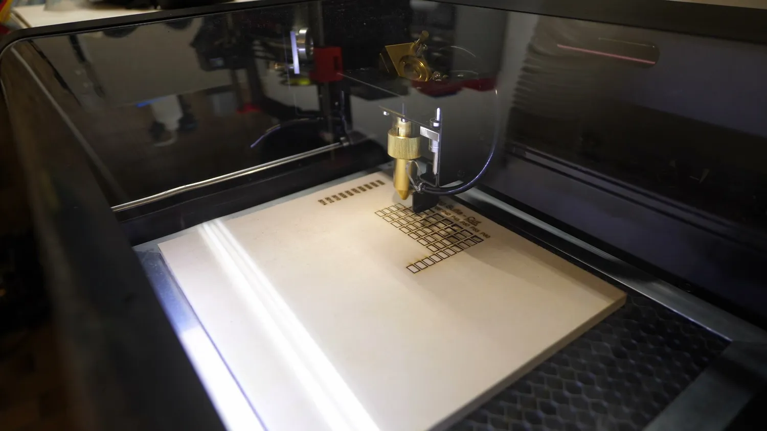 CO2 laser head engraving a test grid into a sheet of plywood