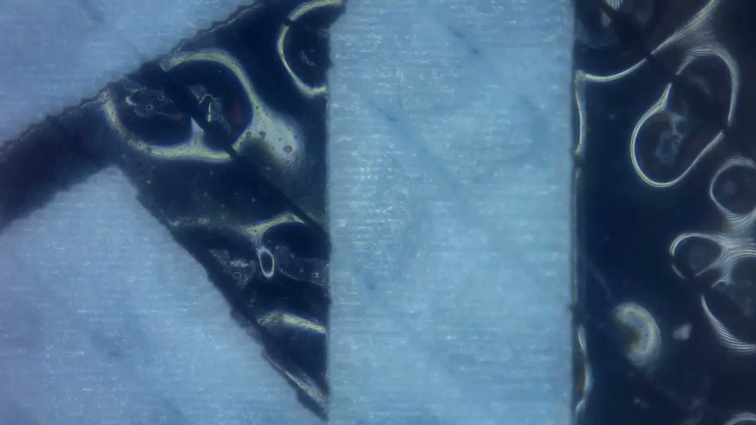 Microscope image of a marked blue sample showing foamed bubbles inside the engraved area
