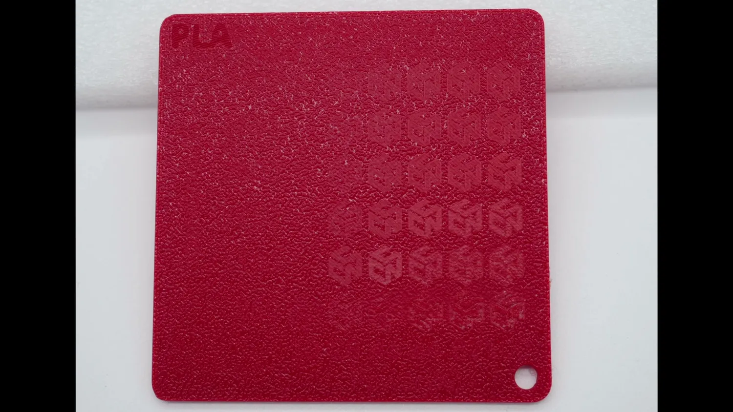 Red PLA test plate where the laser marked logos are barely visible