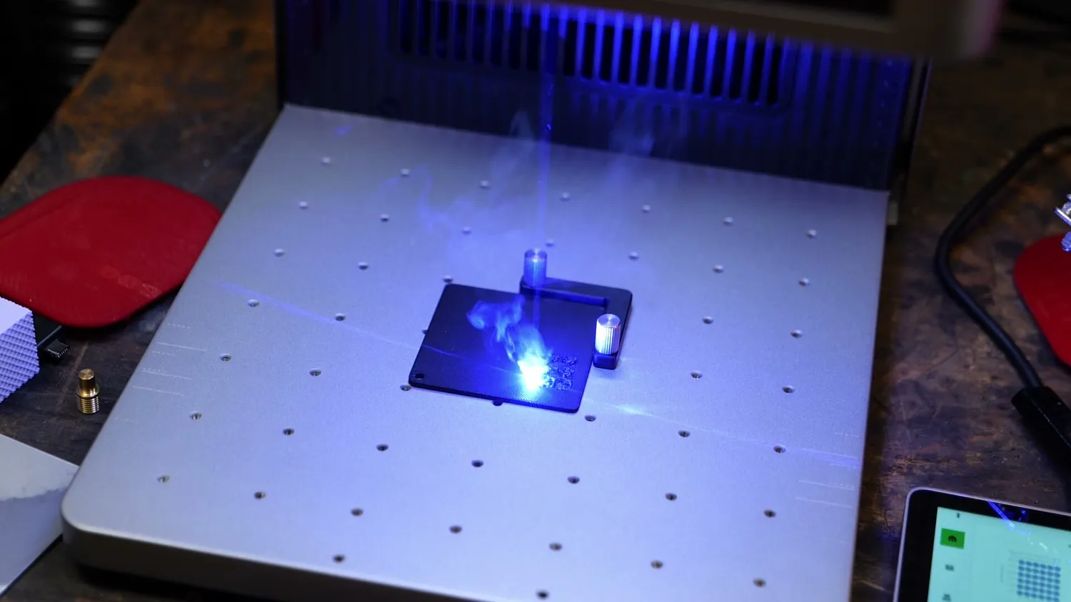 Blue diode laser melting the surface of a dark test plate inside the machine