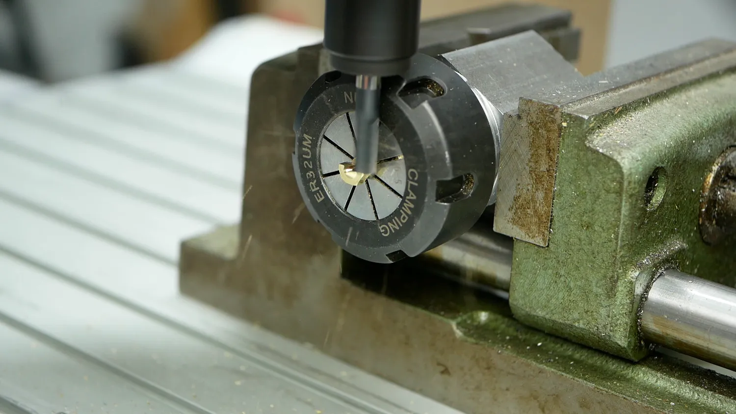 The nozzle held in an ER32 collet block clamped in the vice, with the end mill cutting the first pass down its centre
