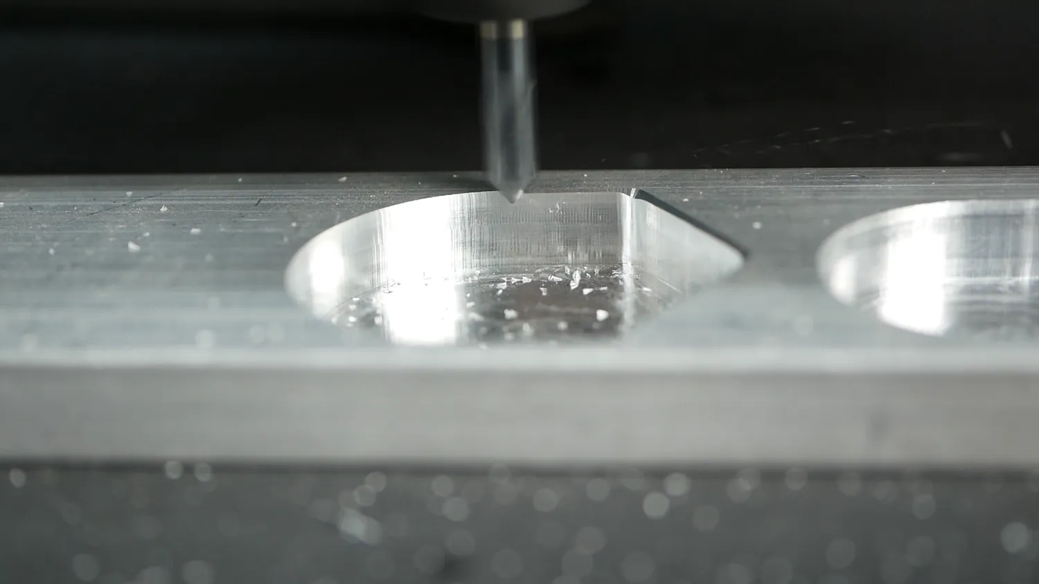 A chamfer cutter opening out a hole in aluminium, a single clean chip curling away