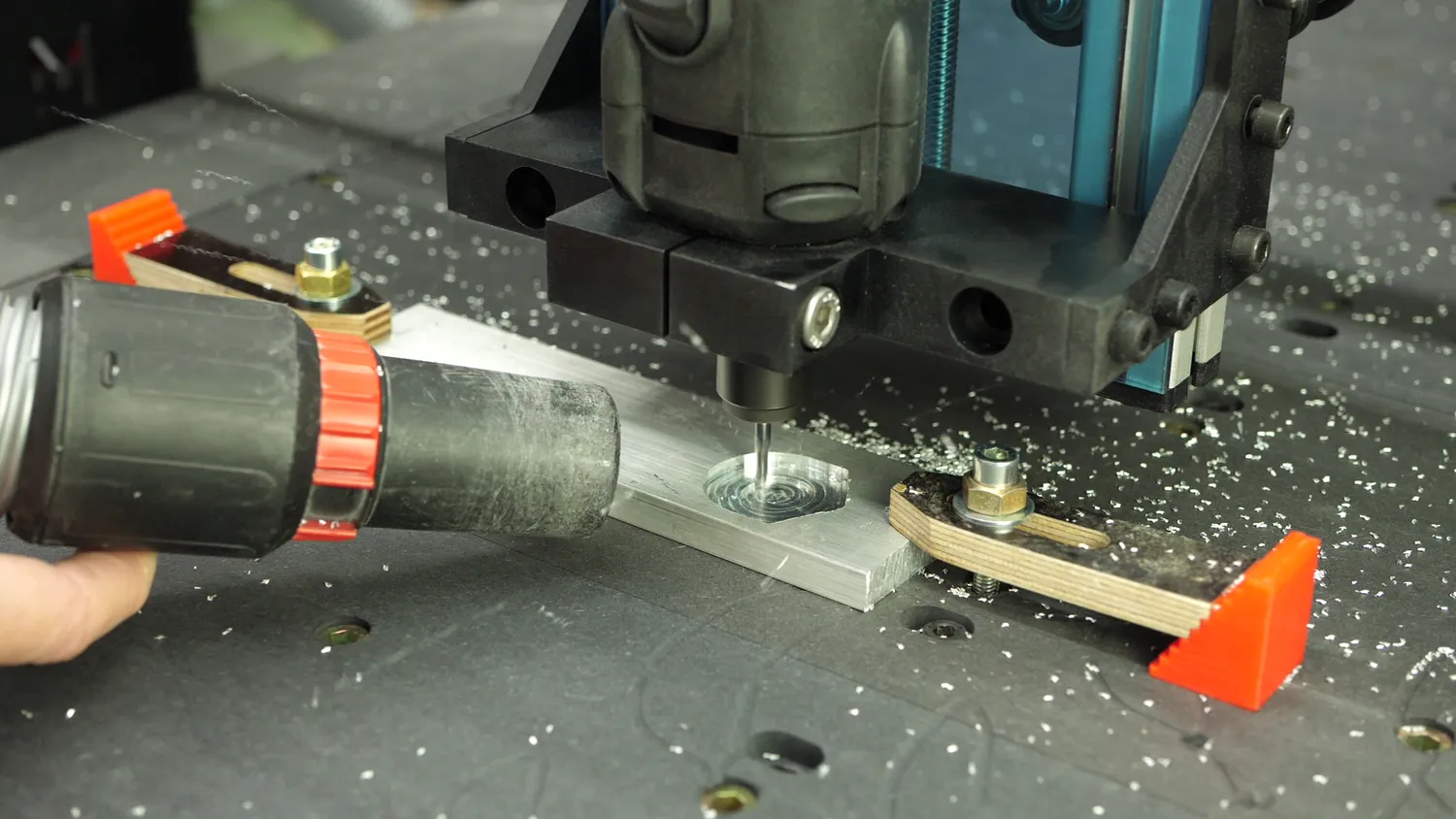 The finished aluminium bar clamped on the bed with printed cam clamps, chips being blown off with an air gun