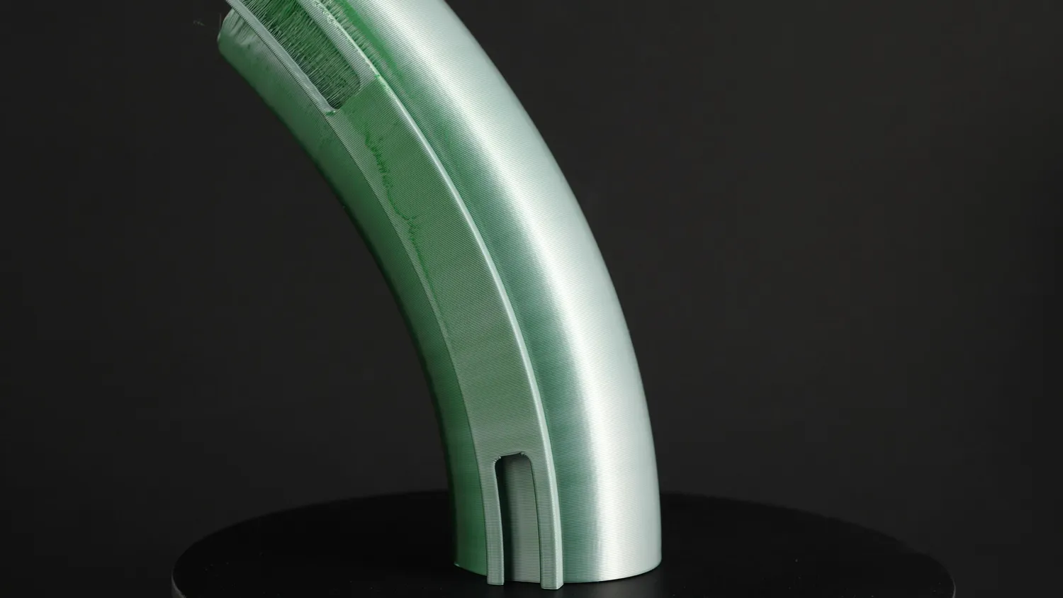 A green bent section from the side, layers running smoothly around the curve