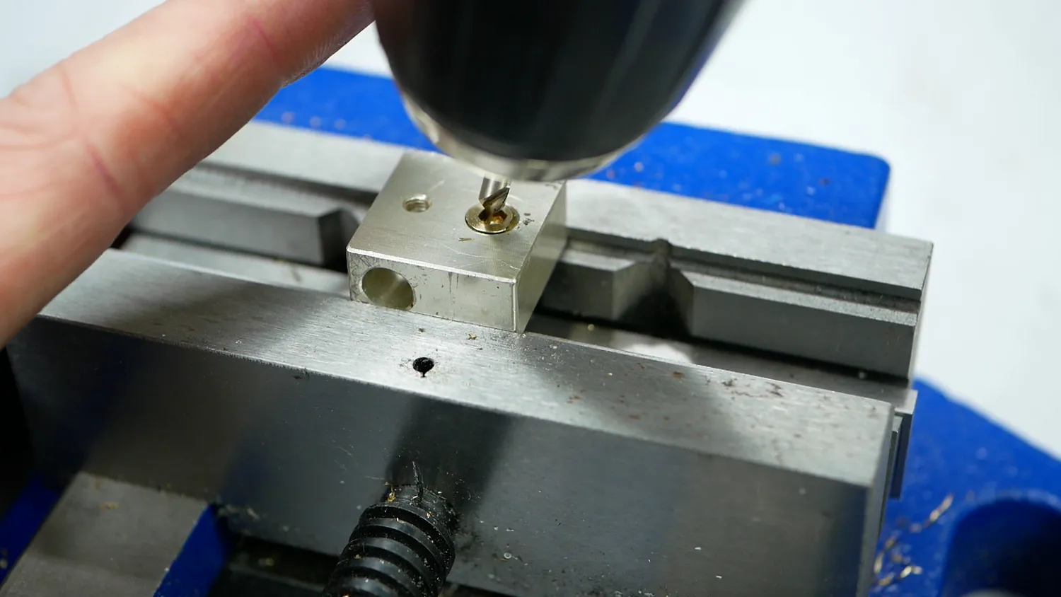 Spotting the hole with a centre drill in the mini-lathe, the block clamped in a vice