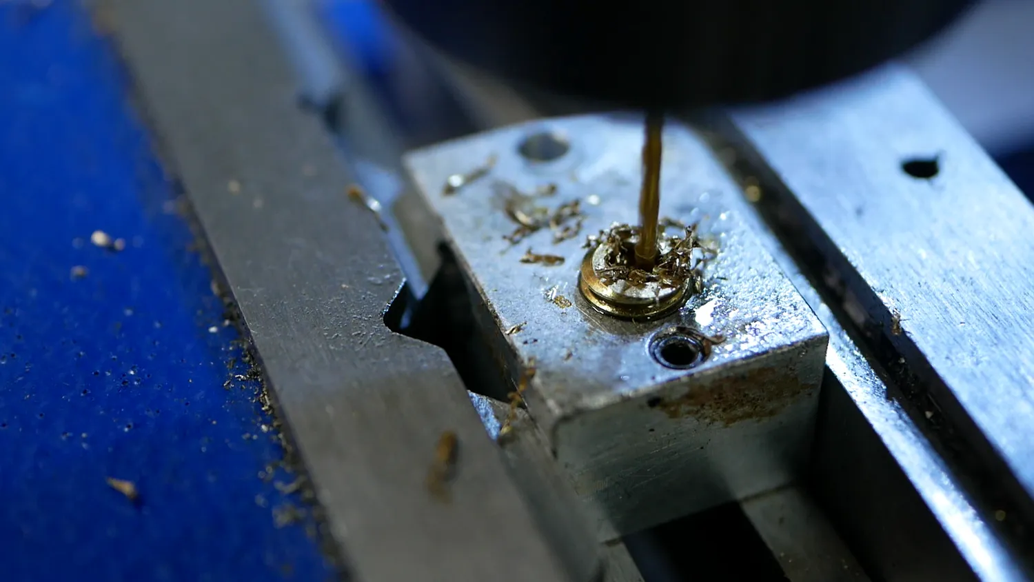 Drilling one of the 1.2 mm bores, with brass swarf curling out of the hex
