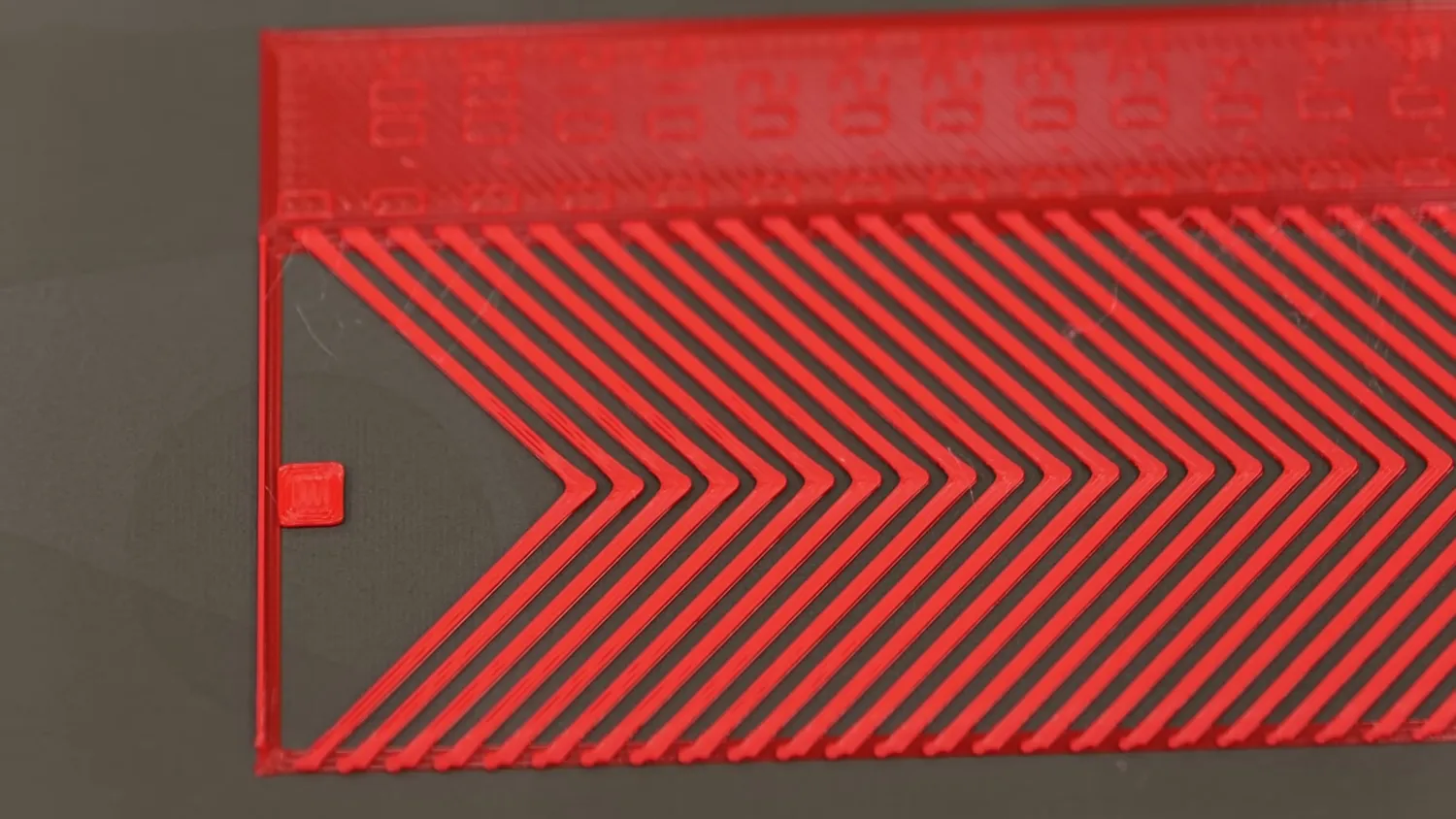 A red pressure advance test pattern printed on the bed, its chevrons stepping across the plate