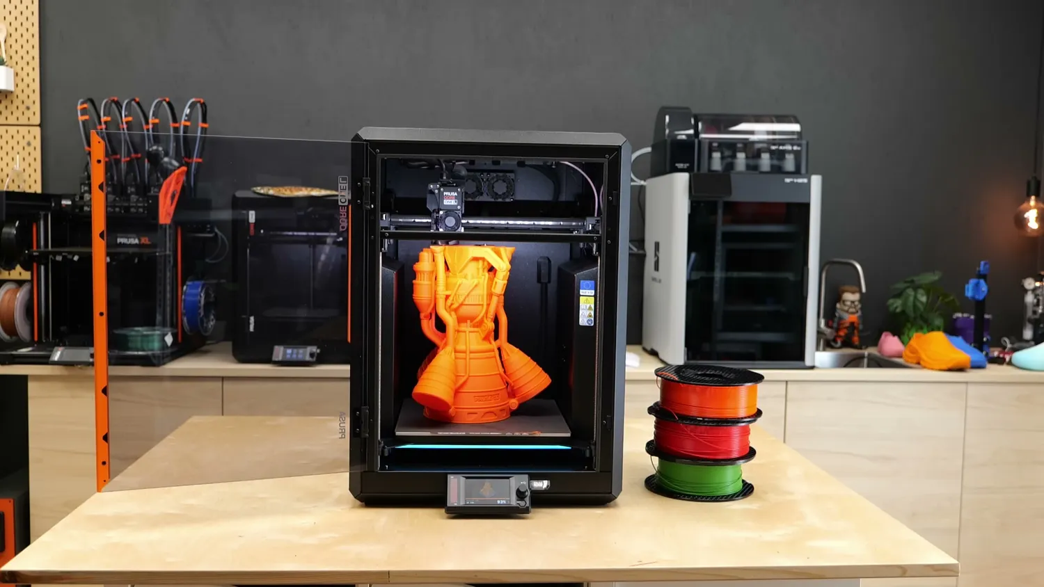 The CORE One L on the studio bench, with a Bambu Lab machine and a Prusa XL in the background