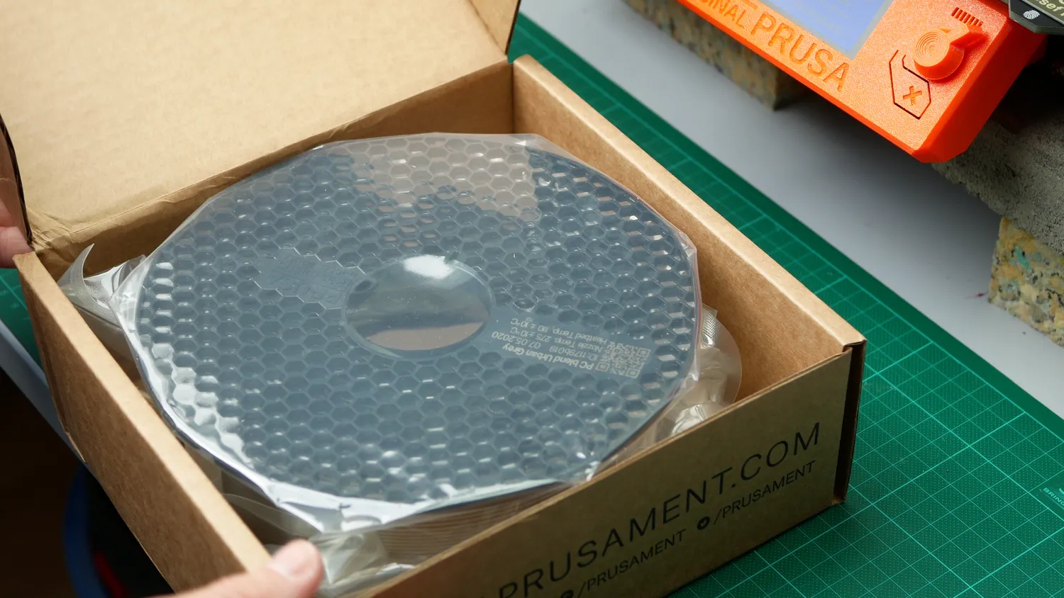 A spool of grey Prusament PC Blend in its box, still sealed in the vacuum bag
