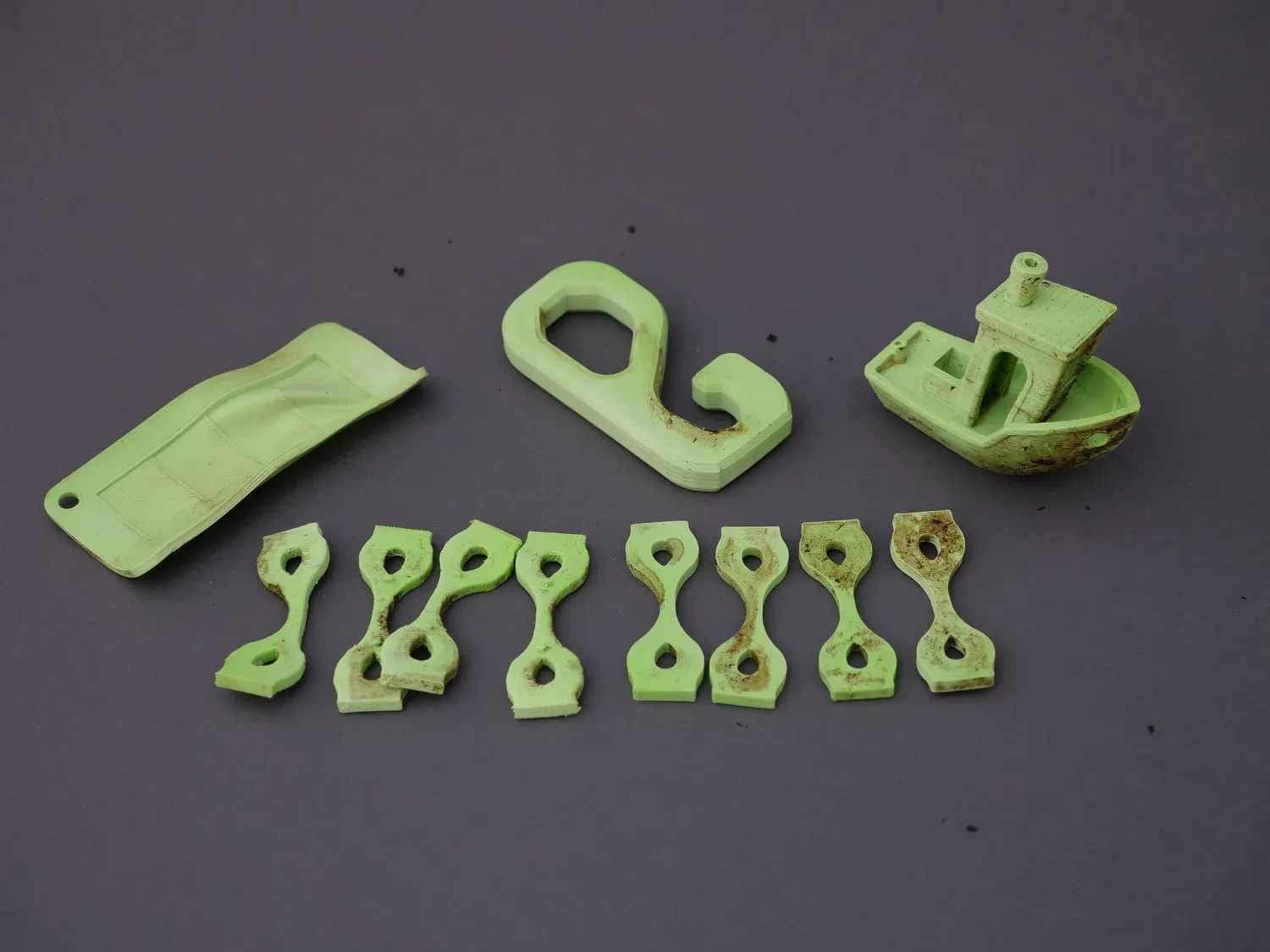 The green PLA samples after the compost, faded and soil-stained but structurally intact