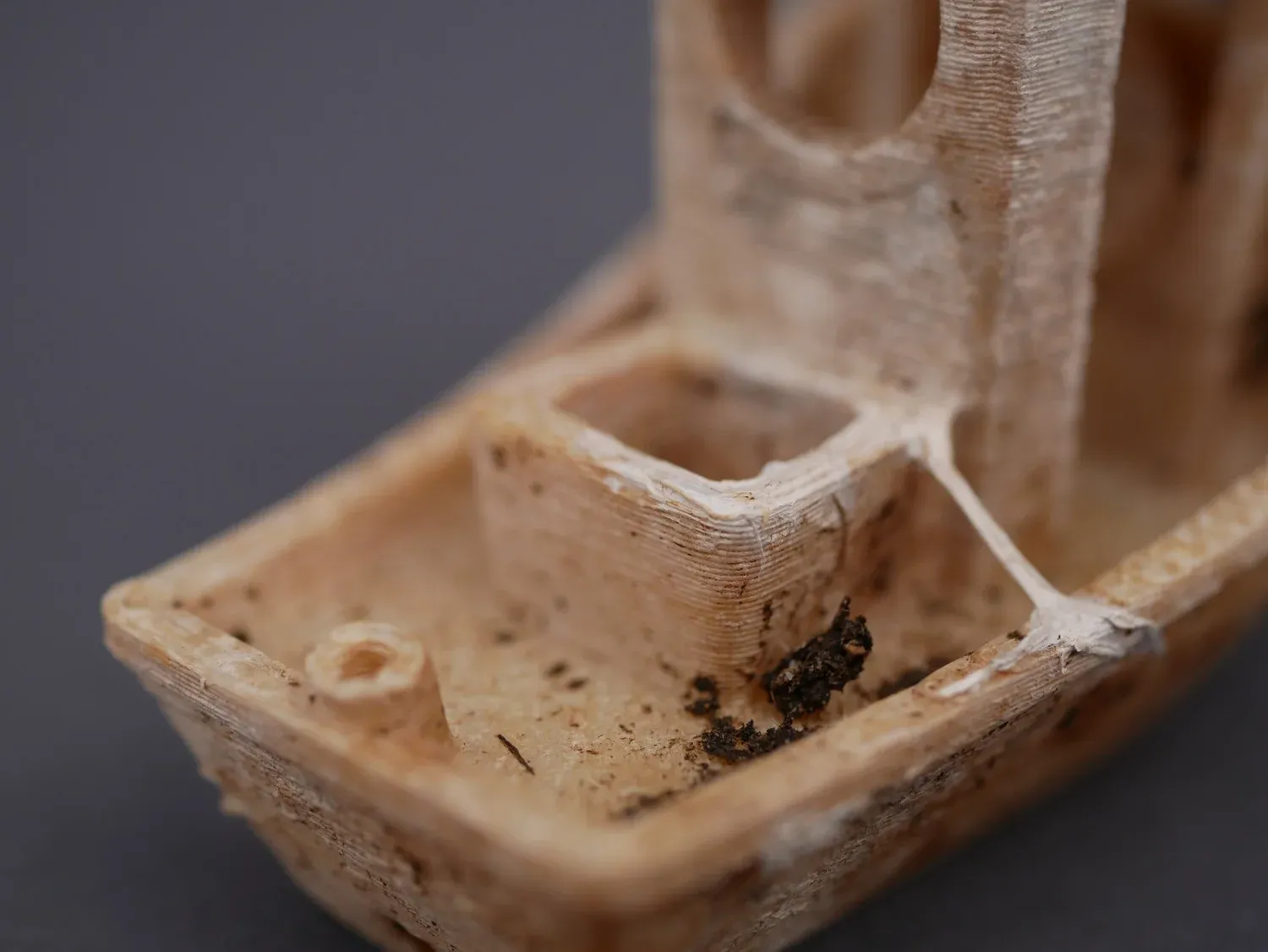 The NonOilen 3DBenchy gone yellow-brown, with chunks of material missing from the hull