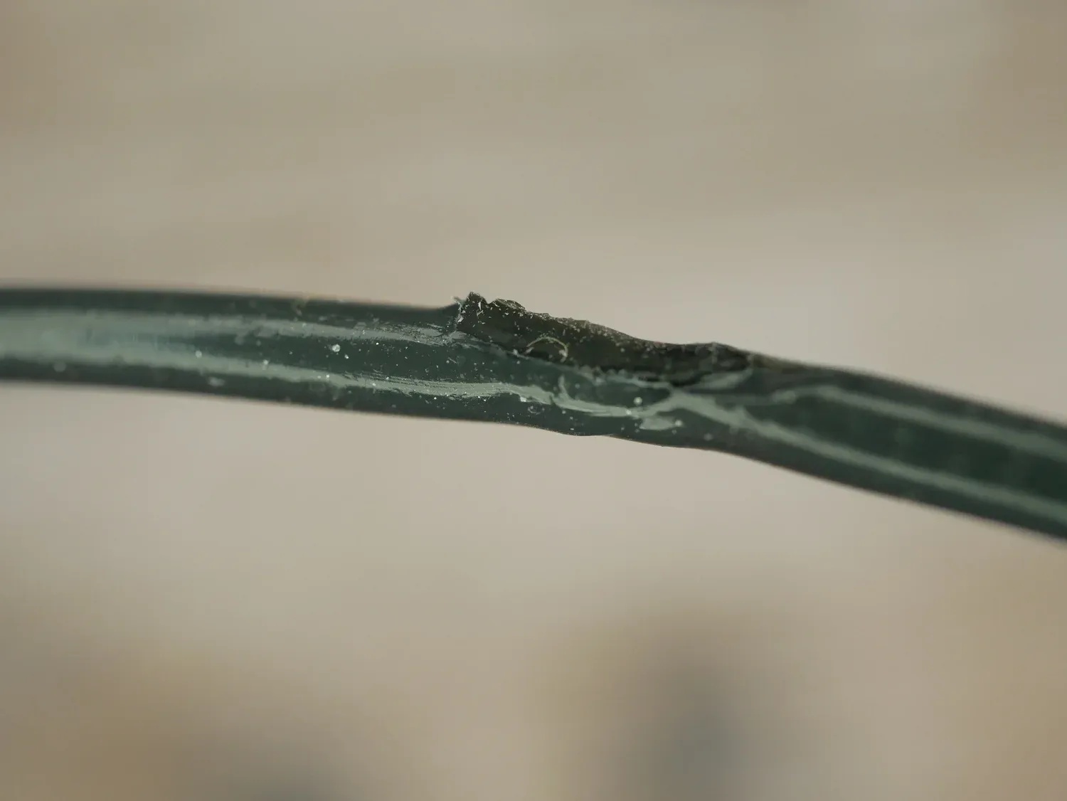 A stretch of the recycled dark green filament with a rough, blistered patch where a contaminant sat in the melt