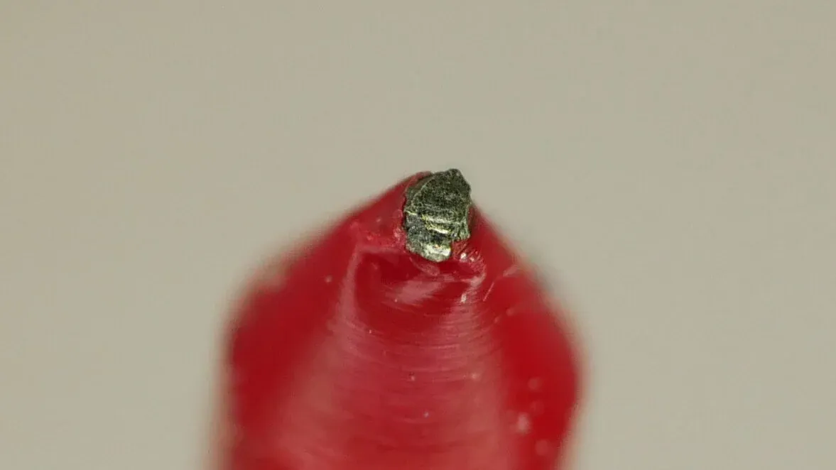 A metal shaving stuck in the tip of a strand of red recycled filament, the piece that eventually jammed the nozzle