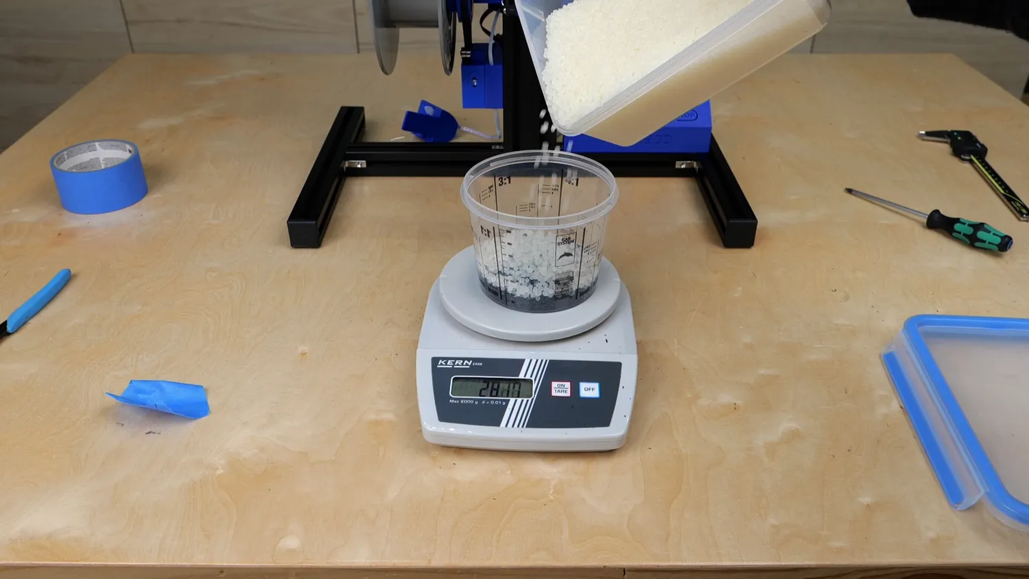 Virgin PLA pellets being poured onto the scale to make up the 50/50 mix with the shredded cutlery