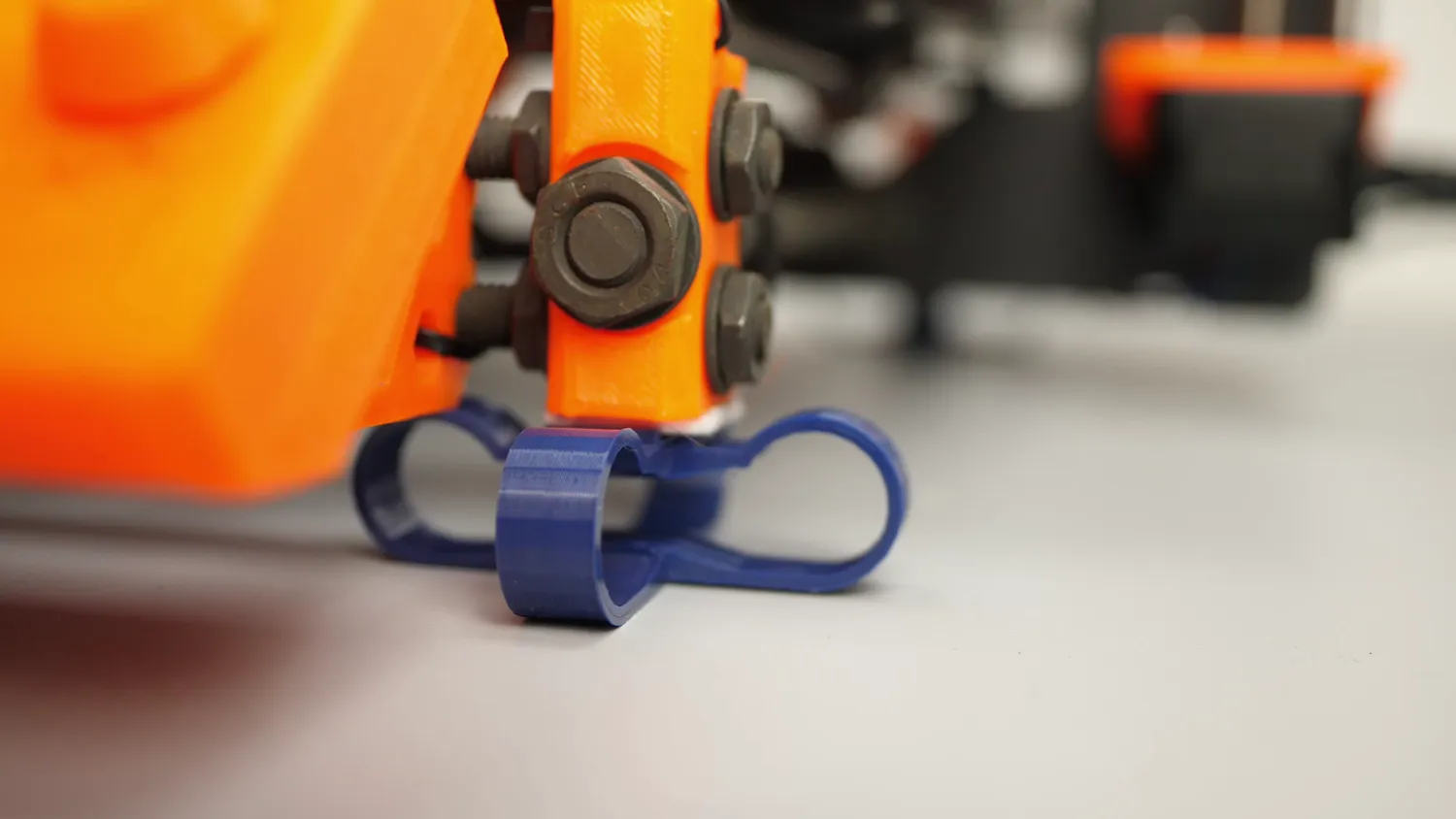 A printed blue spring foot under the orange corner of a printer frame
