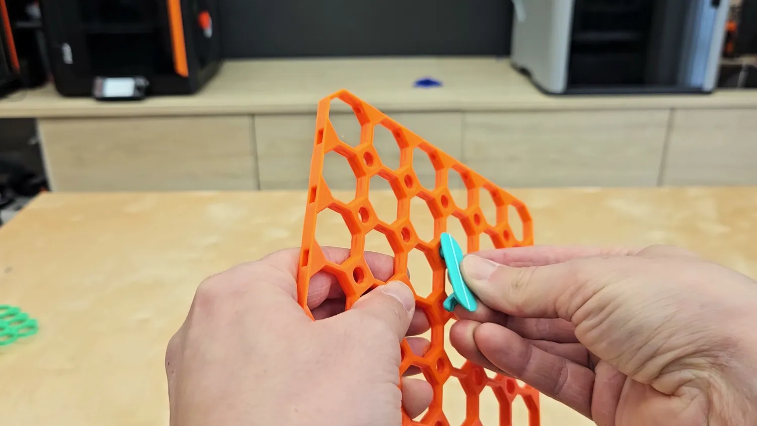 Folded Multiboard clip being pushed into an orange baseboard