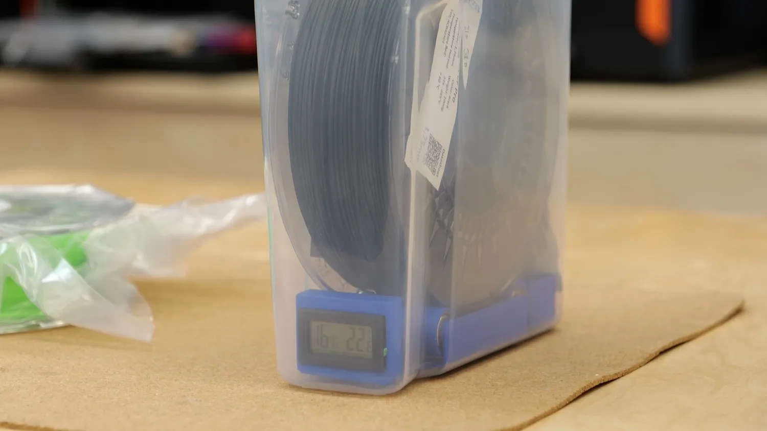 A cereal container with a spool of filament and a small hygrometer