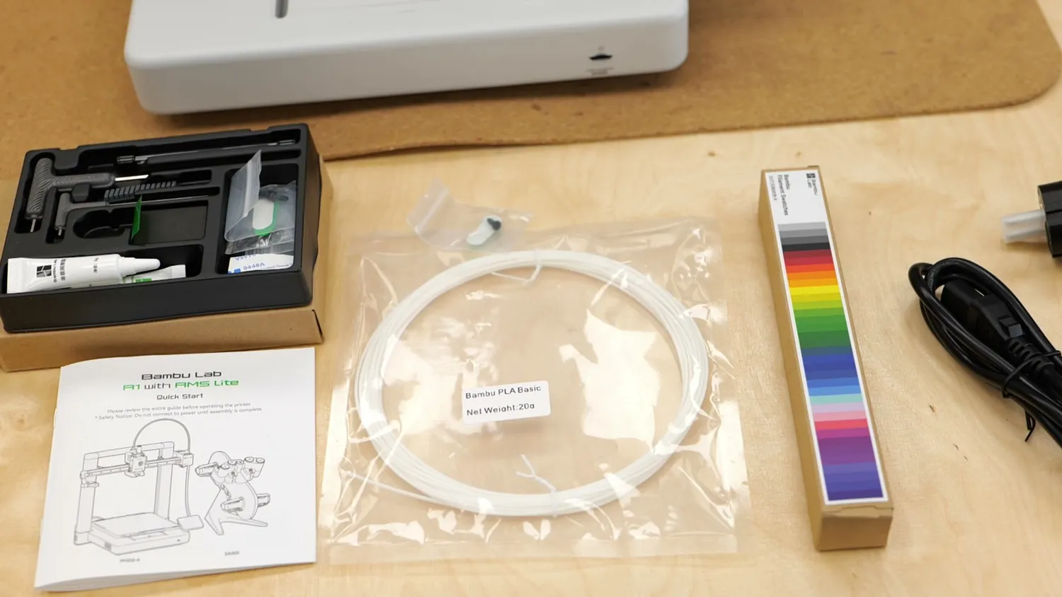 Included toolkit, quick-start guide, sample filament and cables unpacked on a workbench