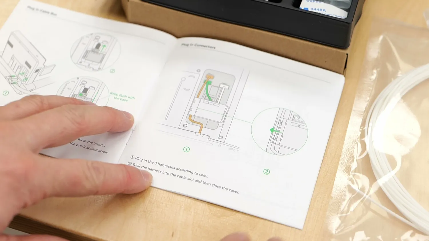 Hands turning the pages of a printed 3D printer quick-start guide